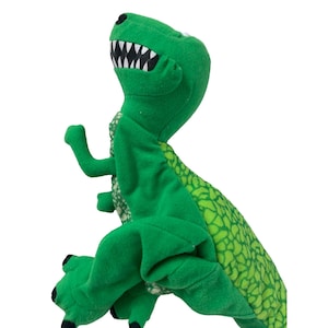 May include: Green plush dinosaur puppet with a toothy grin and a scaly back. The puppet has a large head and a long tail.