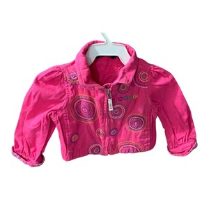 May include: A pink denim jacket with a zipper closure and colorful embroidered circles. The jacket has a collared neckline and long sleeves. The word "C&C" is embroidered on the front of the jacket.
