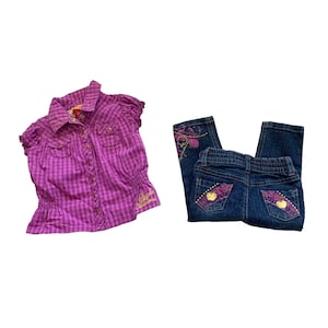 May include: A purple and white plaid button-up shirt with short sleeves and the text "Apple Bottom" in gold lettering. A pair of blue denim jeans with purple and gold embroidered hearts and embellishments.