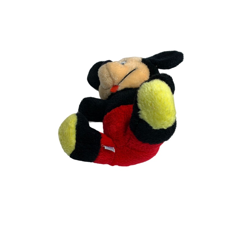 Może przedstawiać: Pluszowa zabawka Mickey Mouse z czarnymi uszami, czerwono-czarnym ciałem i ż&oacute;łtymi stopami. Zabawka siedzi na białym tle.