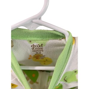 Puede incluir: Un pelele blanco y verde para beb&eacute; con ribete verde. El pelele tiene un estampado de animales de dibujos animados amarillos y verdes. La etiqueta dice "child of mine from the makers of carter's 0-9 months".