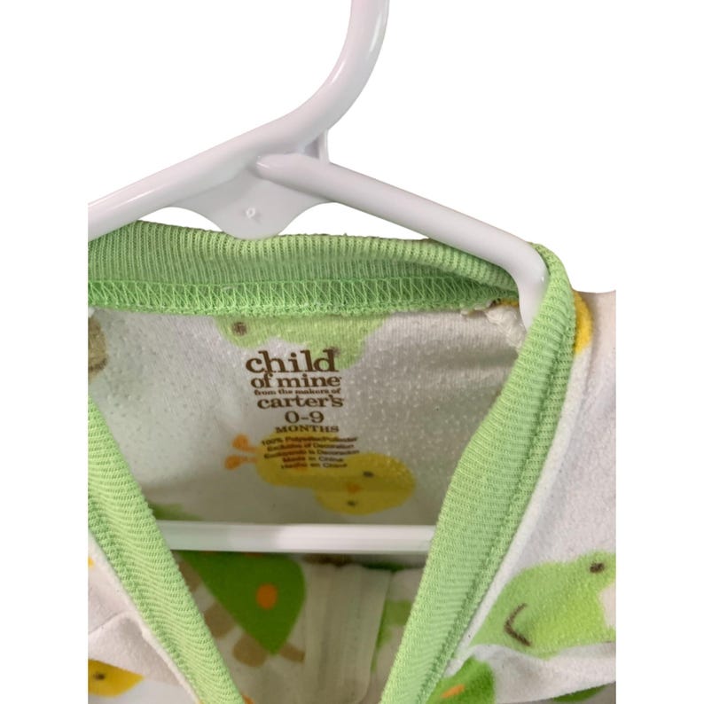 Puede incluir: Un pelele blanco y verde para beb&eacute; con ribete verde. El pelele tiene un estampado de animales de dibujos animados amarillos y verdes. La etiqueta dice "child of mine from the makers of carter's 0-9 months".