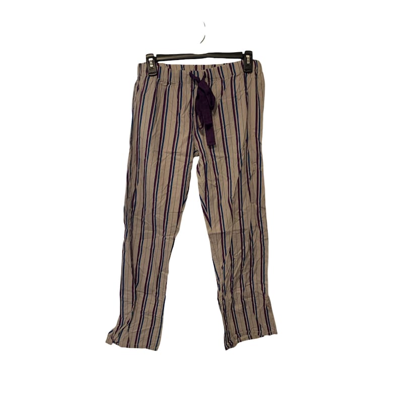 May include: Tan and purple striped pajama pants with a drawstring waist. The pants are hanging on a black hanger against a white background. The vertical stripes are purple and a darker tan color.
