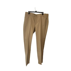 May include: Khaki-colored pants hanging on a black hanger. The pants have a button closure and a classic, straight-leg design. The fabric appears to be a medium-weight material, suitable for casual or semi-formal wear. The pants are displayed against a white background.