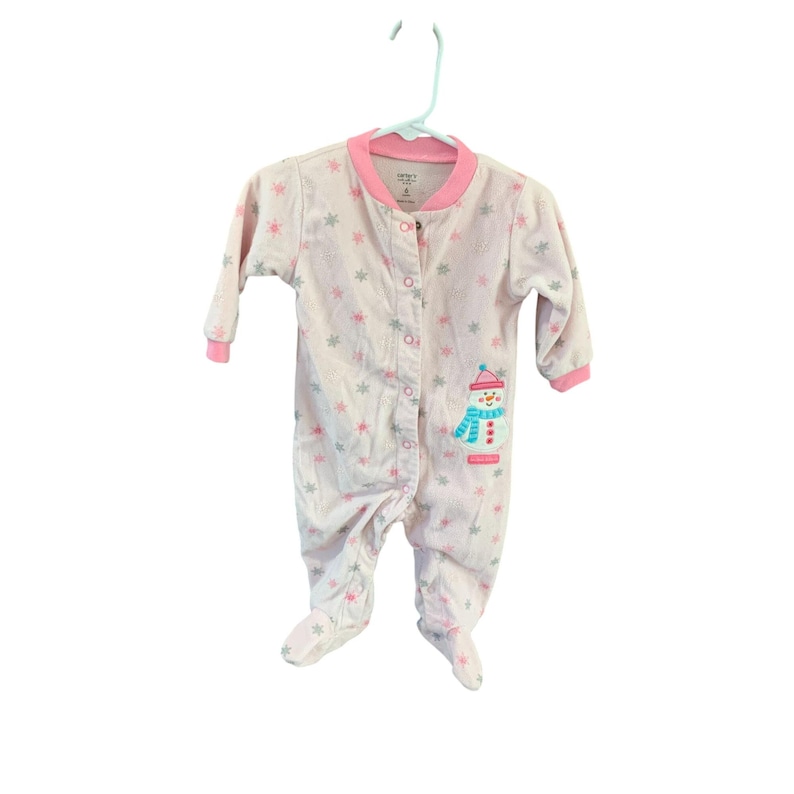 May include: Pink and white baby sleeper with a snowman design and snowflake print. The sleeper has a pink trim and a button closure.