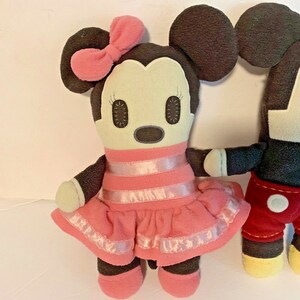 Pu&ograve; includere: Un paio di peluche di Topolino e Topolina. Topolina indossa un vestito rosa a righe bianche e un fiocco rosa. Topolino indossa pantaloni rossi e scarpe gialle.