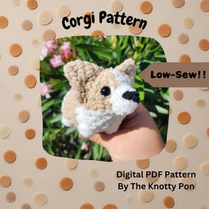 May include: A crochet pattern for a Corgi dog, with a low-sew design. The pattern is digital and available as a PDF download. The pattern is by The Knotty Pon.