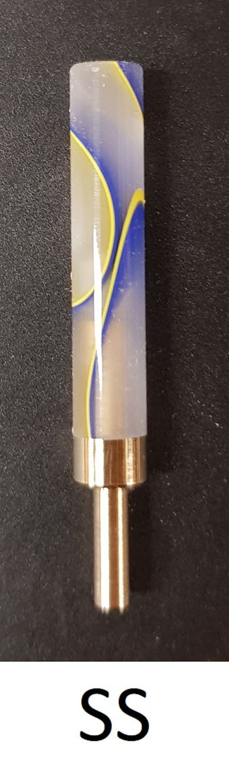 May include: A close-up of a white, blue, and yellow striped pen with a gold metal tip. The pen is on a black surface. SS