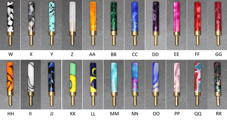 May include: Twenty-four different colored and patterned pen barrels with gold-colored metal tips. The barrels are arranged in two rows of twelve.