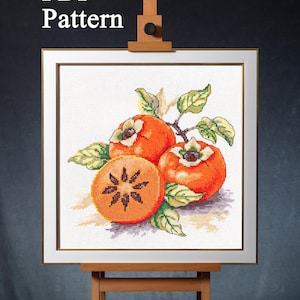 May include: A cross-stitch pattern featuring three orange persimmons with green leaves on a white background. The pattern is framed and displayed on an easel. The text "PDF Pattern" is visible at the top of the image.