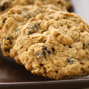 Op de afbeelding: Close-up van een bord met havermout-rozijnenkoekjes. De koekjes zijn goudbruin en hebben een kauwbare textuur. Ze zijn in een rij op het bord gerangschikt.