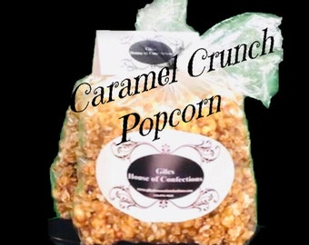 May include: A clear plastic bag filled with caramel crunch popcorn. The bag has a white label with a black oval and text that reads "Giles House of Confections". The text "Caramel Crunch Popcorn" is written on the bag. The website www.gileshouseofconfections.com is also visible.
