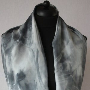 Op de afbeelding: Een grijze en witte tie-dye infinity sjaal gemaakt van zachte stof.