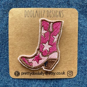 May include: Pink cowboy boot with white stars embroidered on it. The boot is on a brown card with the text "DOOLALLY DESIGNS" and "prettydoolally@etsy.co.uk" printed on it.