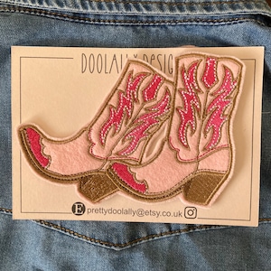 May include: Pink and brown embroidered cowboy boot patch with a white background. The patch has the text "DOOLALLY DESIGN" and "prettydoolally@etsy.co.uk" on it.