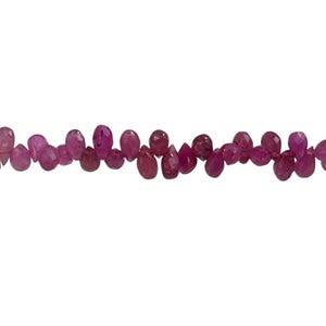 May include: A strand of pink and magenta gemstone beads. The beads are teardrop-shaped and vary in size, strung together to create a necklace or bracelet. The background is plain white.