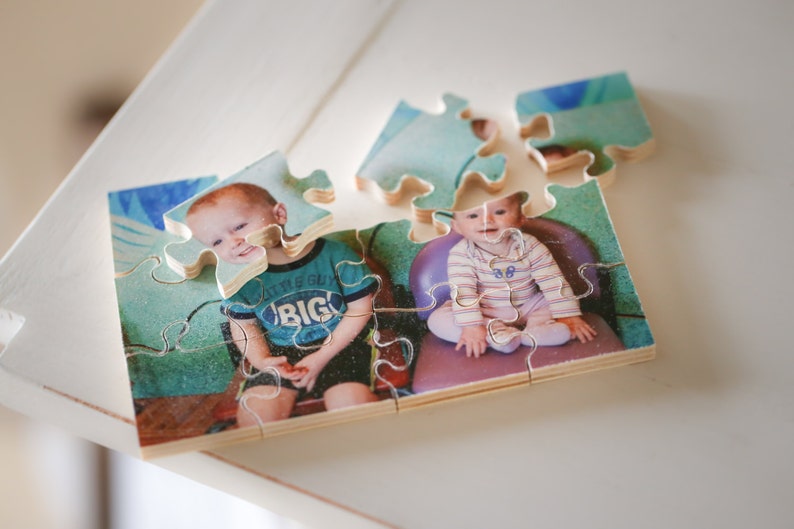 May include: A wooden jigsaw puzzle with a photo of two children. The child on the left is wearing a blue shirt with the words "Little Boy Big" printed on it. The child on the right is wearing a striped shirt. The puzzle is partially assembled.