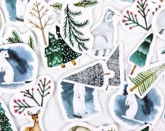 Könnte beinhalten: Eine Sammlung von Aquarell-Stickern mit verschiedenen winterlichen Illustrationen, darunter ein Reh, ein Fuchs, ein Waschbär, eine Kiefer und eine Schneelandschaft.