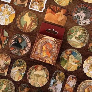 Könnte beinhalten: Eine Bogen mit Aufklebern im Vintage-Stil mit Illustrationen von Frauen in verschiedenen Posen und Umgebungen. Die Aufkleber sind rund, rechteckig und oval und in verschiedenen Farben gehalten, darunter Gold, Braun und Weiß. Die Aufkleber eignen sich perfekt, um Tagebüchern, Planern und anderen Bastelprojekten einen Hauch von Vintage-Charme zu verleihen.