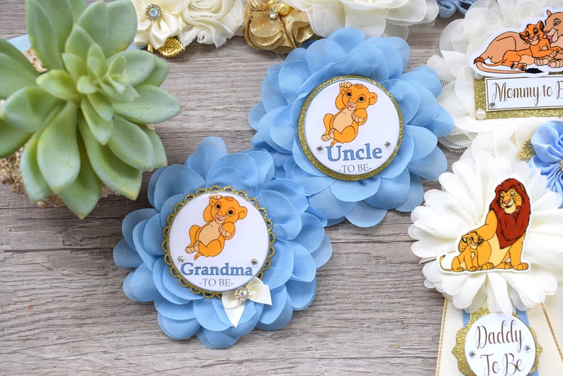 Pu&ograve; includere: Decorazioni per baby shower a forma di fiore azzurro chiaro a tema Simba. Le decorazioni includono una succulenta, rosette e badge con le scritte "Nonna", "Zio", "Mamma" e "Pap&agrave;".