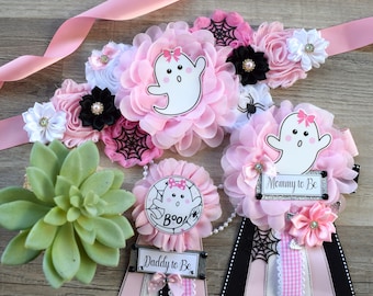 Könnte beinhalten: Rosa und schwarze Babyparty-Schärpen zum Thema Halloween mit Geister- und Spinnennetz-Dekorationen. Die Schärpen sagen "Mommy to Be" und "Daddy to Be".