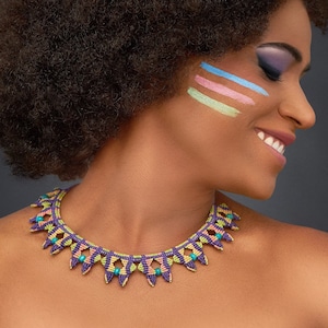 May include: A woman with an afro hairstyle and colorful makeup on her cheek is wearing a purple, green, and pink beaded necklace.