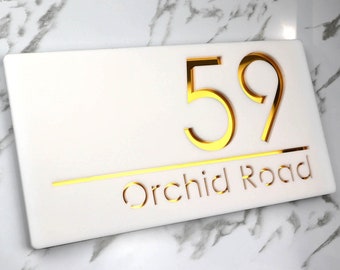 May include: White rectangular house number sign with gold numbers "59" and the text "Orchid Road" in gold.