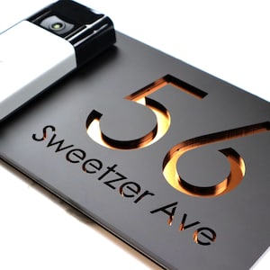 Könnte beinhalten: Ein schwarzes Hausnummernschild mit der Nummer 56 und dem Straßennamen "Sweetzer Ave", die in Gold ausgeschnitten sind.