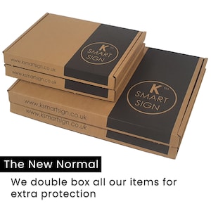 Puede incluir: Dos cajas de cart&oacute;n marr&oacute;n apiladas una encima de la otra. Las cajas est&aacute;n etiquetadas con el texto "K SMART SIGN" y la direcci&oacute;n del sitio web "www.ksmartsign.co.uk". El texto "The New Normal" est&aacute; impreso debajo de las cajas. El texto "We double box all our items for extra protection" est&aacute; impreso debajo del texto "The New Normal".