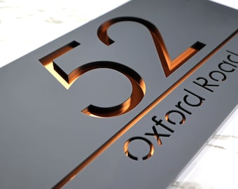 May include: Gray house number sign with the number 52 and the street name "Oxford Road" cut out in a copper color.