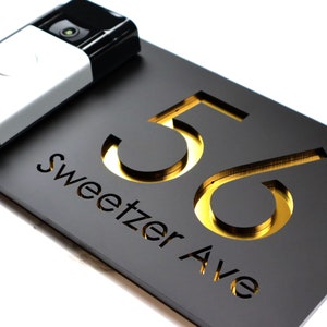 May include: Black house number plaque with gold lettering. The plaque reads "56 Sweetzer Ave".