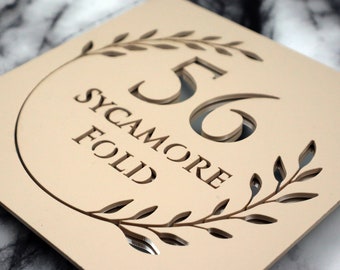 Letrero K Smart / Floral S1 / Letrero decorativo cuadrado para casa en beige, caqui y crema mate, con número de puerta y espejo plateado y flor.