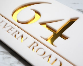 May include: White house number sign with gold lettering. The number 64 is cut out of the sign and the background is gold. The text "Wern Road" is cut out of the sign and the background is gold.