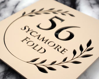 Letrero K Smart / Floral S1 / Letrero decorativo cuadrado para casa en beige, caqui y crema mate, con número de puerta de mármol negro y flor.