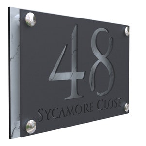 Puede incluir: Un letrero de número de casa gris oscuro con el número 48 y el texto "SYCAMORE CLOSE" en blanco. El letrero tiene remaches de metal plateado alrededor de los bordes.