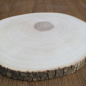 May include: A round wooden slice with a natural bark edge. The wood is light brown with visible grain patterns.