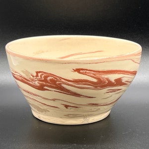 May include: A white ceramic bowl with a marbled design in shades of brown and cream.