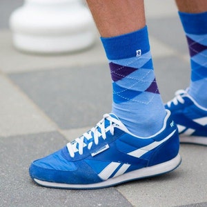 Könnte beinhalten: Blaue und weiße gemusterte Socken mit einem blauen und weißen Reebok-Turnschuh. Der Turnschuh hat ein weißes Reebok-Logo an der Seite.