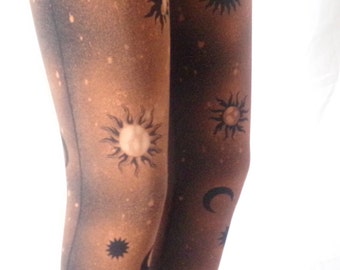 May include: Brown leggings with a black and white sun and moon print. The print is a galaxy-like design with stars and moons.