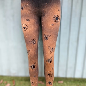 May include: Black leggings with a brown ombre effect and a bee and honeycomb pattern.