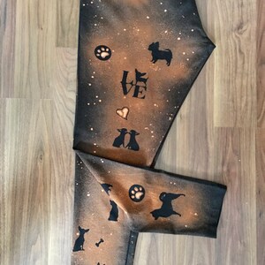 May include: Black leggings with a bleach-splattered design featuring silhouettes of dogs, paw prints, and the word "LOVE".