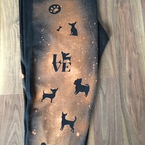 May include: Black sweatpants with a bleach-splattered design featuring a paw print, a bone, the word "LOVE", and multiple silhouettes of small dogs.