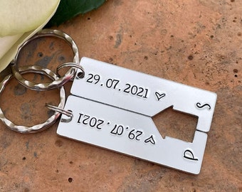 May include: Two silver-toned rectangular metal keychains featuring a cutout house shape in the center. Each piece is engraved with the date 29.07.2021, a small heart symbol, and the letters S and P. The keychains are attached to circular metal rings.