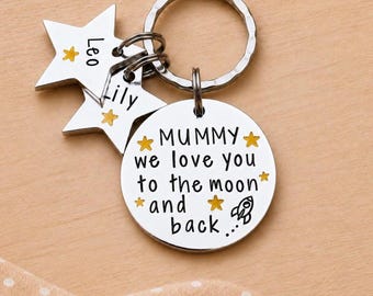 May include: A silver-toned metal keychain featuring a circular disc engraved with the text MUMMY we love you to the moon and back, accompanied by two star-shaped charms engraved with the names Leo and Lily, all accented with small yellow stars.