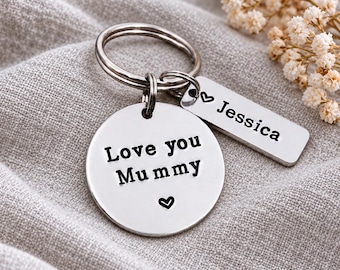 May include: A silver-toned metal keyring featuring a circular disc engraved with the text Love you Mummy and a small heart symbol, accompanied by a rectangular tag engraved with the name Jessica and a small heart symbol.