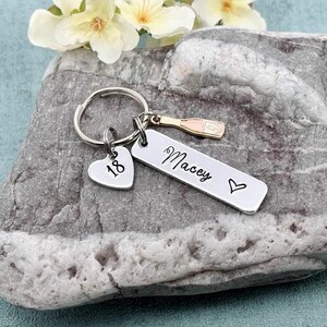 May include: Silver keyring with a heart charm that says "18", a bar charm that says "Macey" with a small heart, and a champagne bottle charm.