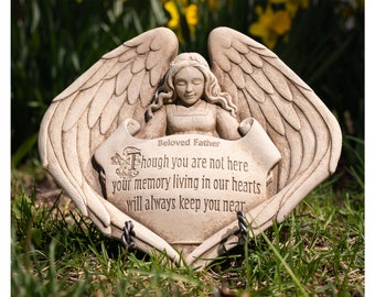May include: A stone angel figurine with wings holding a scroll with the inscription "Beloved Father Though you are not here your memory living in our hearts will always keep you near".