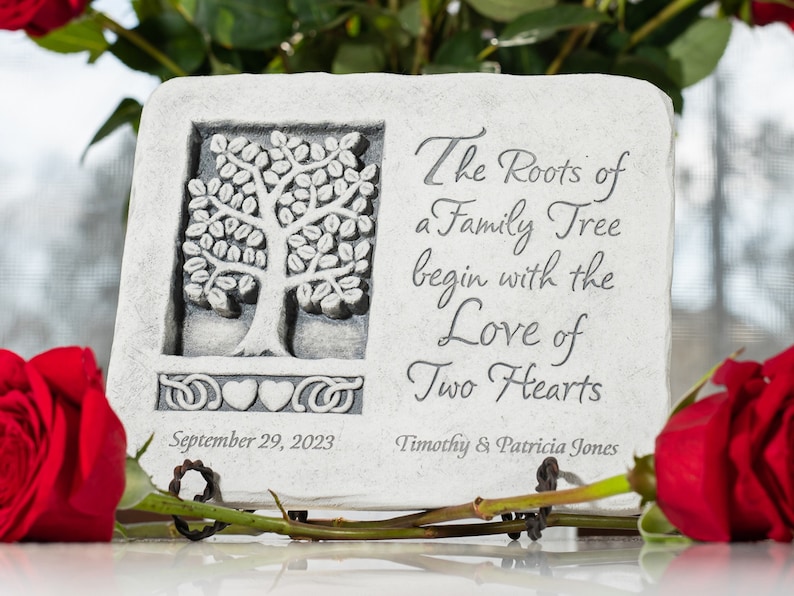 May include: A white stone plaque with a carved tree design and the text "The Roots of a Family Tree begin with the Love of Two Hearts". The plaque also includes the date "September 29, 2023" and the names "Timothy & Patricia Jones".