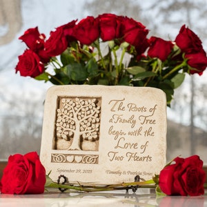 May include: A white stone plaque with a carved tree design and the inscription "The Roots of a Family Tree begin with the Love of Two Hearts". The plaque is decorated with a heart and a Celtic knot. The date "September 29, 2023" and the names "Timothy & Patricia Jones" are also inscribed on the plaque. The plaque is surrounded by red roses.
