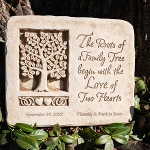 May include: A beige stone garden plaque with a carved tree design and the inscription "The Roots of a Family Tree begin with the Love of Two Hearts". The plaque also includes the date "September 29, 2023" and the names "Timothy & Patricia Jones".